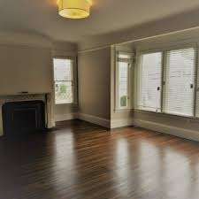 An empty room with wooden floors, a fireplace, and large windows, listed by Morley Fredericks Real Estate Inc. in San Rafael.
