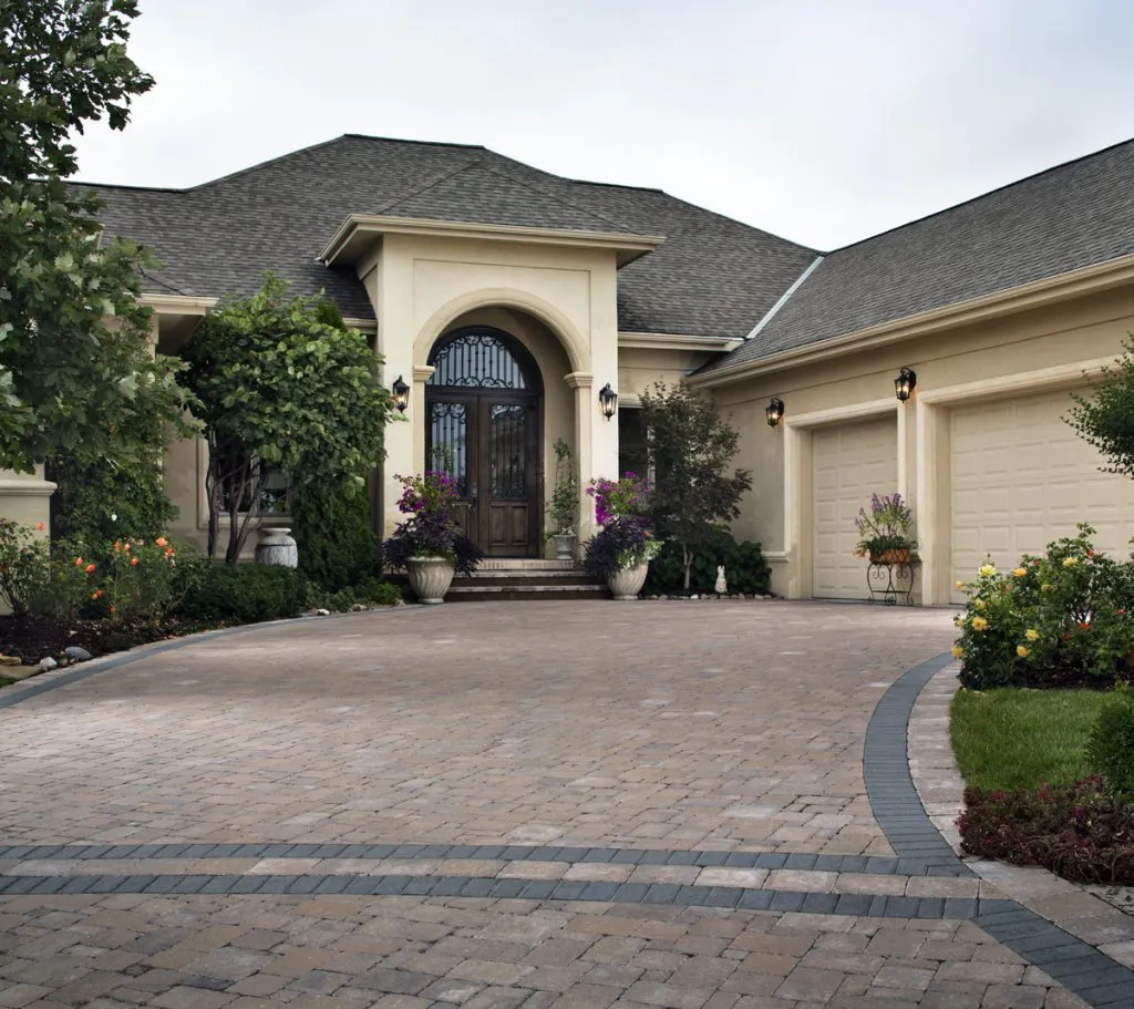 A beautifully paved driveway leading to a luxurious house with a manicured garden, installed by Mr. Pavers Contractor Services, Inc. in Rodeo.