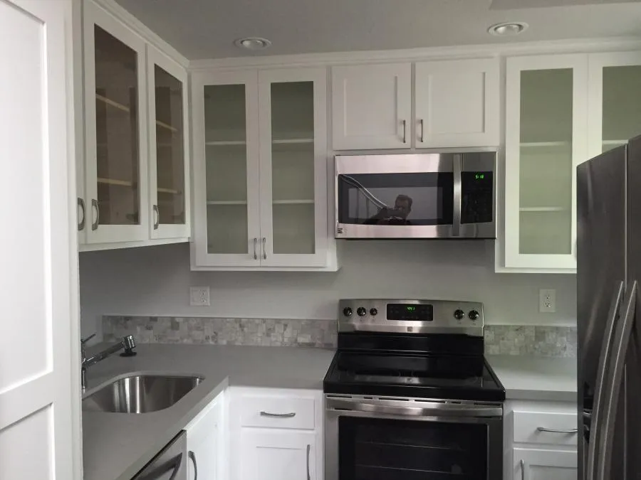 "A modern kitchen with white cabinets, stainless steel appliances, and a tiled backsplash, renovated by NBE Property Restoration in Santa Rosa."