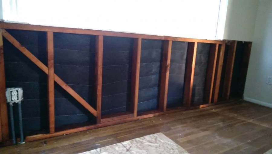 Image of a partially stripped wall showing exposed wooden studs and insulation, illustrating the restoration process by NBE Property Restoration in Santa Rosa.