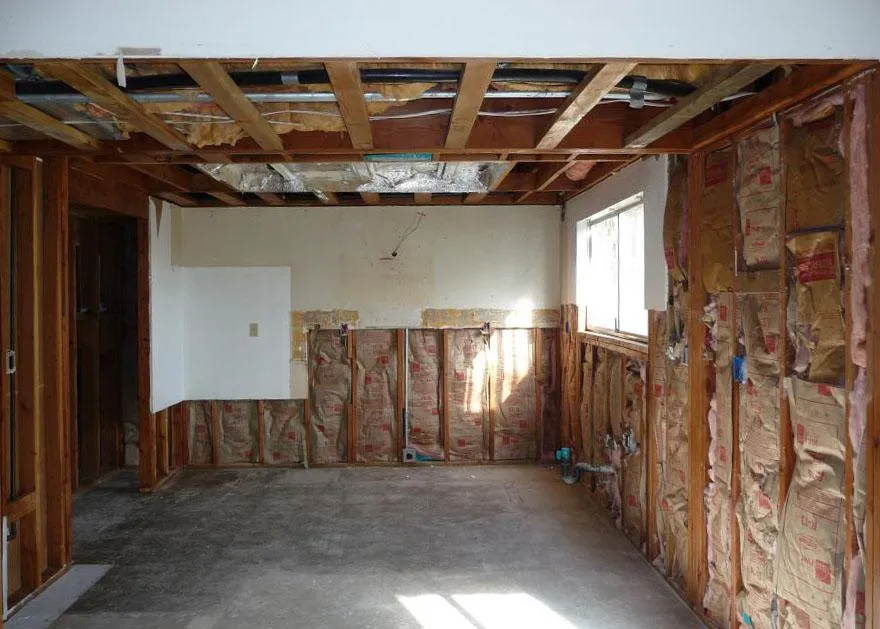 Interior of a partially renovated room with exposed wooden beams and insulation; showcased by NBE Property Restoration in Santa Rosa.