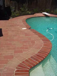 A well-maintained backyard pool with a curved brick paving design by Natural Landscaping Contractors in Concord.