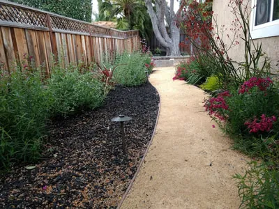 "A well-designed garden path lined with lush greenery and colorful flowers, created by Natural Landscaping Contractors in Concord."