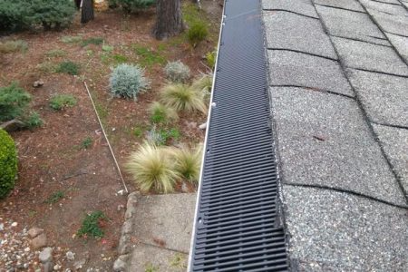 A gutter with a protective guard installed by NorCal Maintenance Inc., showing a well-maintained roofline and garden area in Windsor.
