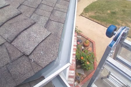 Image of a ladder positioned next to a roof with shingles and a clean gutter, showing NorCal Maintenance Inc.'s work in Windsor.