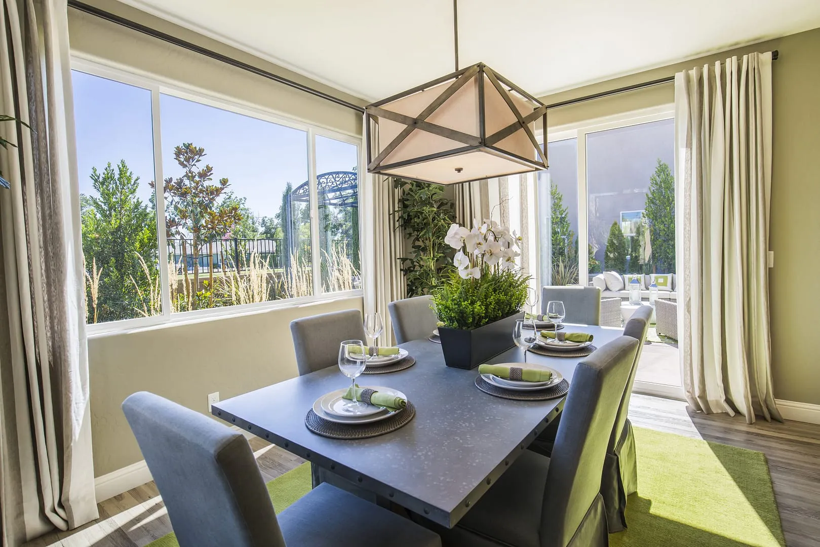 A modern dining room with a table set for four, surrounded by large windows and natural light, designed by Northwest Exteriors in Santa Rosa.