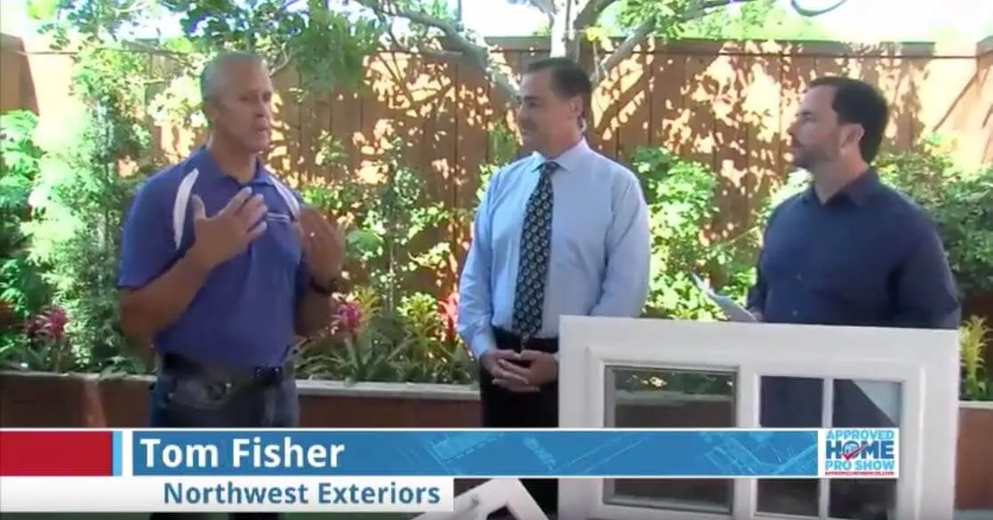 Three men, one holding a window frame, discussing exterior solutions in a garden setting representing Northwest Exteriors in Santa Rosa.