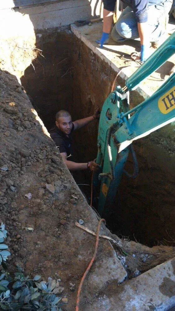 "A plumber from One Source Plumbing and Rooter, Inc. working in a deep trench with an excavator in San Francisco."