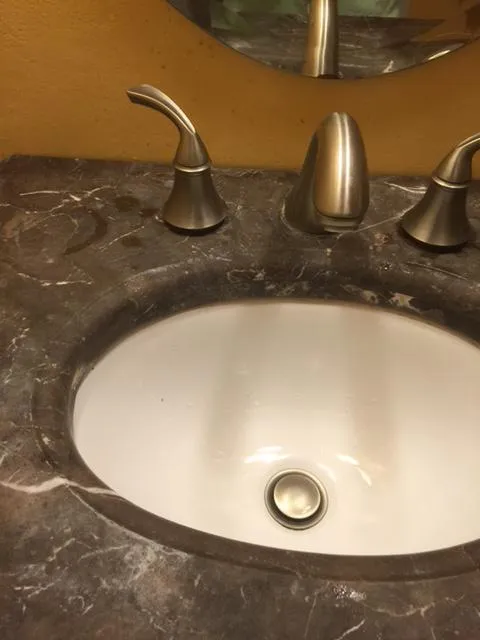 A bathroom sink with a marble countertop, slightly dirty, highlighting the cleaning potential for Optimum Cleaning Services in Sunnyvale.