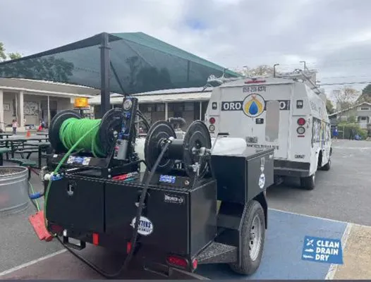 A plumbing service vehicle and equipment trailer belonging to Oro Pro Plumbing, Inc. located in a parking area in South San Francisco.