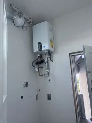 A tankless water heater installed on a wall by Oro Pro Plumbing, Inc. in South San Francisco, featuring pipes and controls.