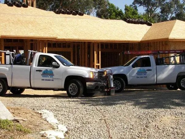 Two Pacific Coast Termite trucks parked in front of a house under construction in Fremont.