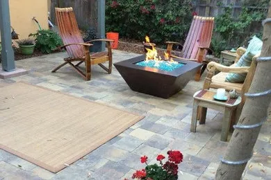 Outdoor patio with wooden chairs and a central fire pit, designed by Pacific Landscaping & Tree Service Inc. in Pacific Grove.