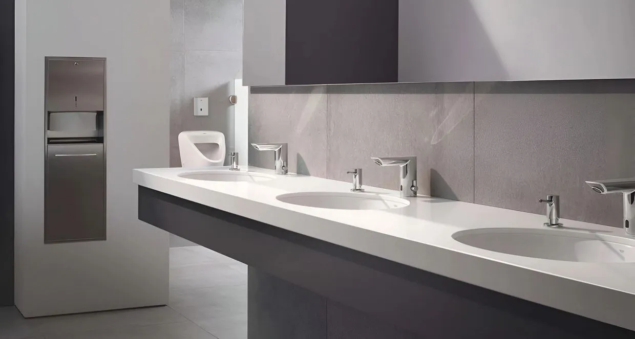 A sleek, modern public restroom with multiple sinks and automated faucets installed by Pacific Plumbing Systems in San Leandro.
