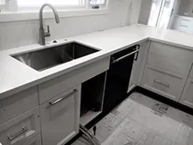 Modern kitchen sink installation with sleek white cabinets and countertops by Pacific Plumbing Systems in San Leandro.