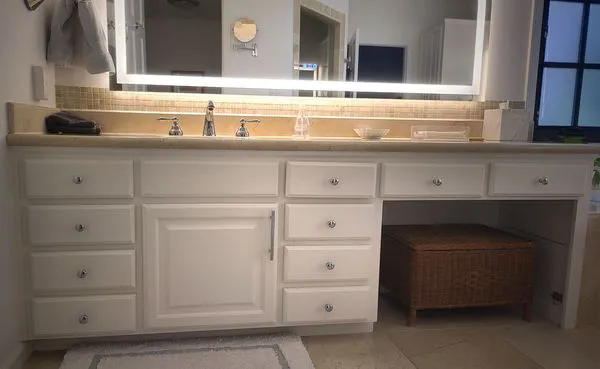 A well-lit bathroom featuring a sleek, white vanity with multiple drawers and a wicker basket underneath, demonstrating Paintmasters' work in Concord.