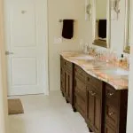 A well-lit bathroom with dual wooden vanities, matching mirrors, and a neutral color scheme, featuring Paintmasters' expert craftsmanship in Concord.