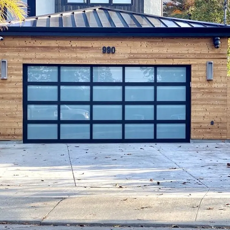 A modern garage with a frosted glass and black frame door, installed by Palms Garage Doors in San Jose, set against a wooden exterior.