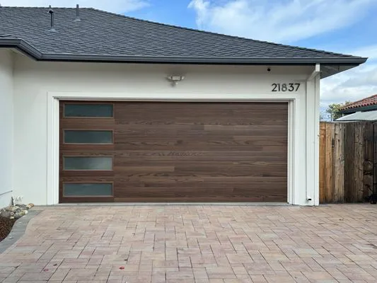 Image of a modern garage door with wood paneling and frosted windows, installed by Palms Garage Doors in San Jose.