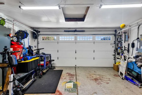 "Interior view of a garage in San Jose, featuring a white sectional garage door installed by Palms Garage Doors, surrounded by organized tools and storage."