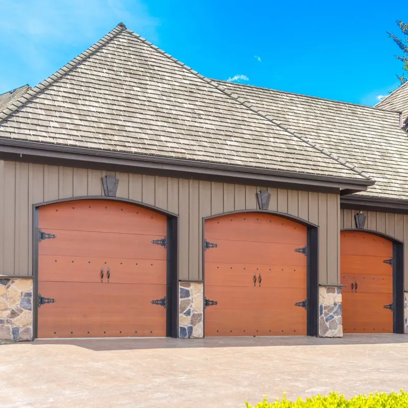 Three wooden garage doors with stone accents and elegant designs, illustrating the quality craftsmanship of Palms Garage Doors in San Jose.