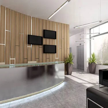 A modern office lobby designed by Peninsula Design and Construction, featuring a sleek reception desk, wood paneling, LCD screens, potted plants, and a polished tile floor in Hayward.