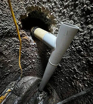 A robust pipe installation emerging from a textured wall, featuring newly fitted white pipes by Pipe Spy Marin, Inc. in Larkspur.