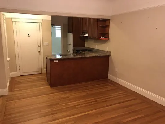 A clean and empty kitchen and living area with wooden floors and modern cabinets, serviced by Premier Janitorial SF in Crockett.