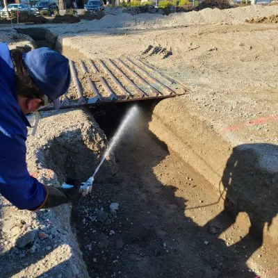A worker from Presto Pest Control, Inc. sprays pest control treatment in a trench at a construction site in San Jose.