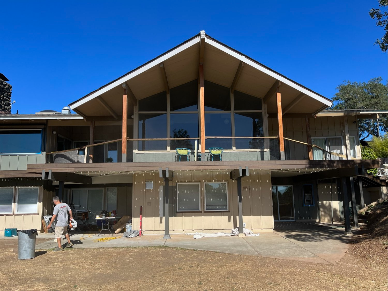 A two-story house in Santa Rosa under renovation by Prime Level Construction, featuring a large A-frame roof, extensive glass windows, and surrounding greenery.