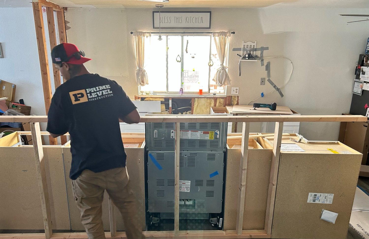 A Prime Level Construction worker in Santa Rosa, focused on installing cabinetry in a partially renovated kitchen space.
