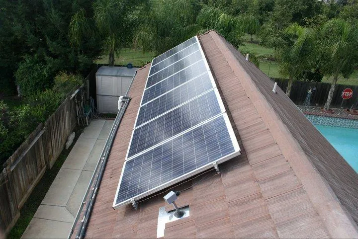 Rooftop solar panels installed by Quality First Home Improvement, Inc. in Citrus Heights, with a view of surrounding greenery and a swimming pool.