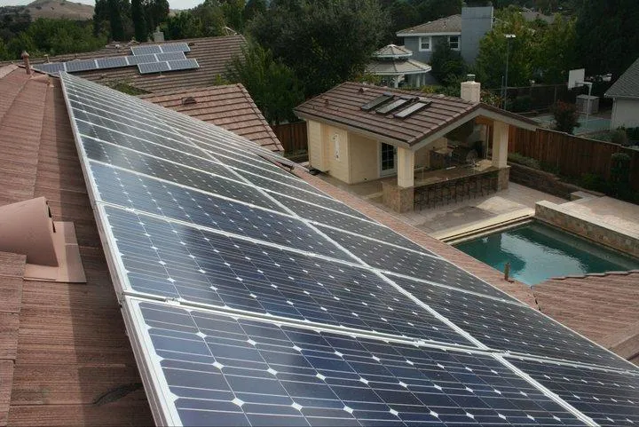 A house roof in Citrus Heights equipped with solar panels installed by Quality First Home Improvement, Inc., overlooking a backyard with a pool and patio.