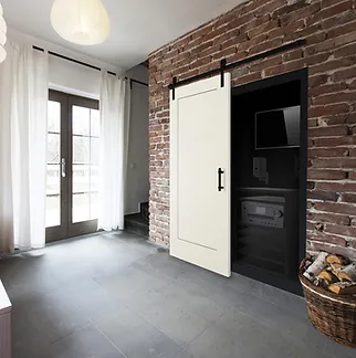 A modern interior featuring a white sliding barn door on a brick wall, with glass doors and sheer curtains opening to a garden.