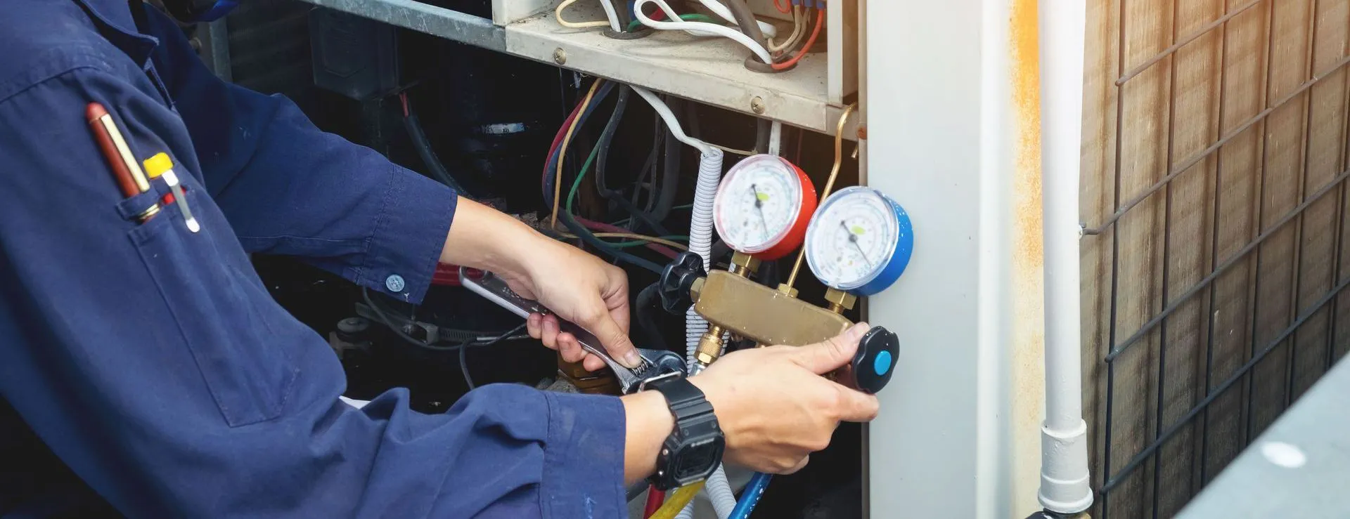 A technician from Qualtech Heating & Cooling in Danville is using tools and gauges to service an HVAC unit.