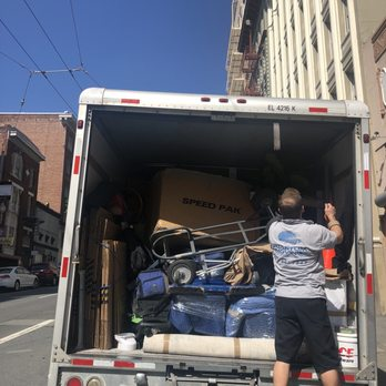 A person organizing items in a fully loaded moving truck under bright sunlight, representing Quantum Moving's service in Martinez.