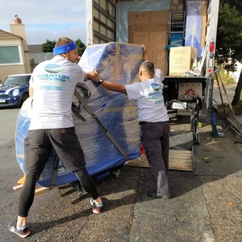 Two movers from Quantum Moving carefully maneuver a large, wrapped item into a moving truck in Martinez.