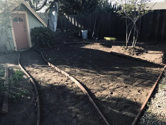Image of a garden area under construction in Santa Cruz with visible pathways, bare soil, and young trees, by Quilici Gardening.