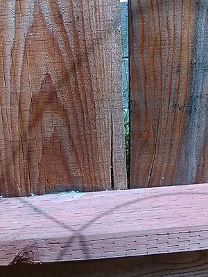 Close-up view of a wooden fence with visible grain patterns and a small gap between the panels.