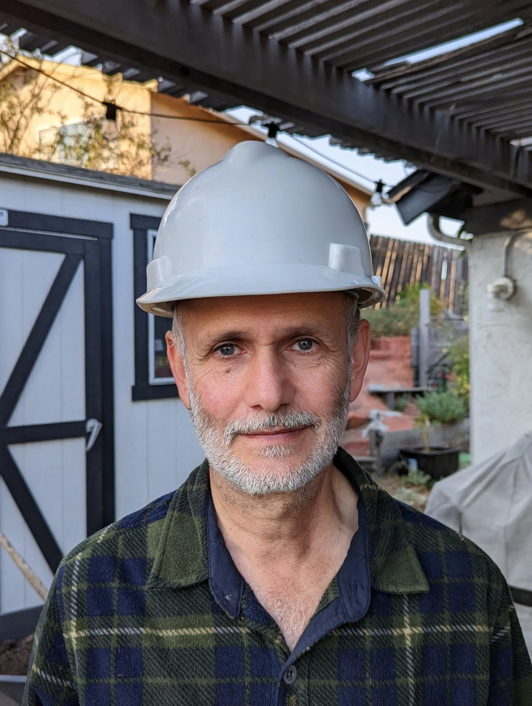A person wearing a hard hat stands outdoors near a building, representing REFCorp in Daly City.