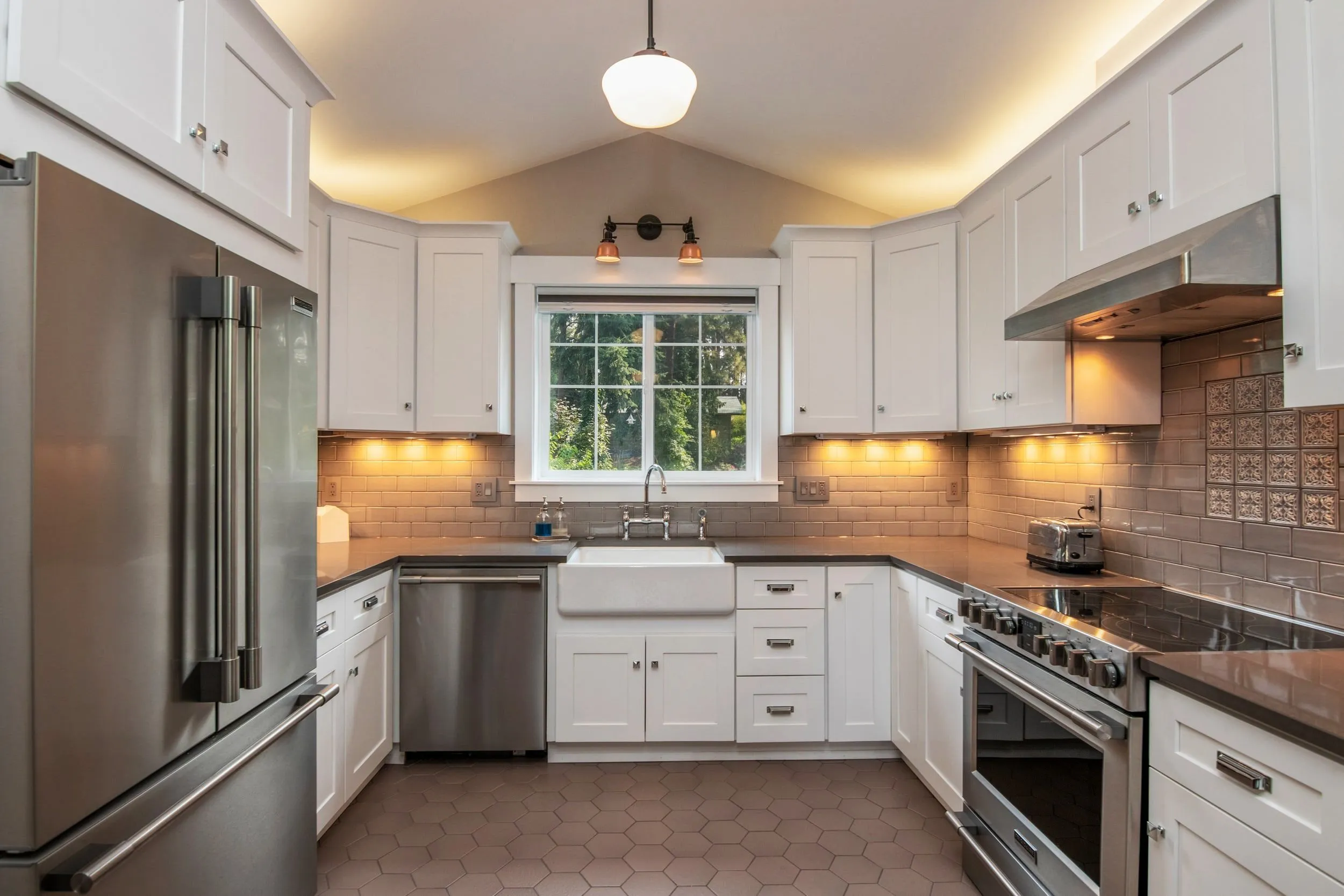 Modern kitchen interior with white cabinets, stainless steel appliances, and a farmhouse sink, designed by REFCorp in Daly City.