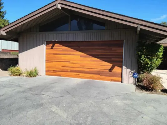 Wooden garage door on a modern house with a sloped roof, installed by R & P Garage Doors in Byron.