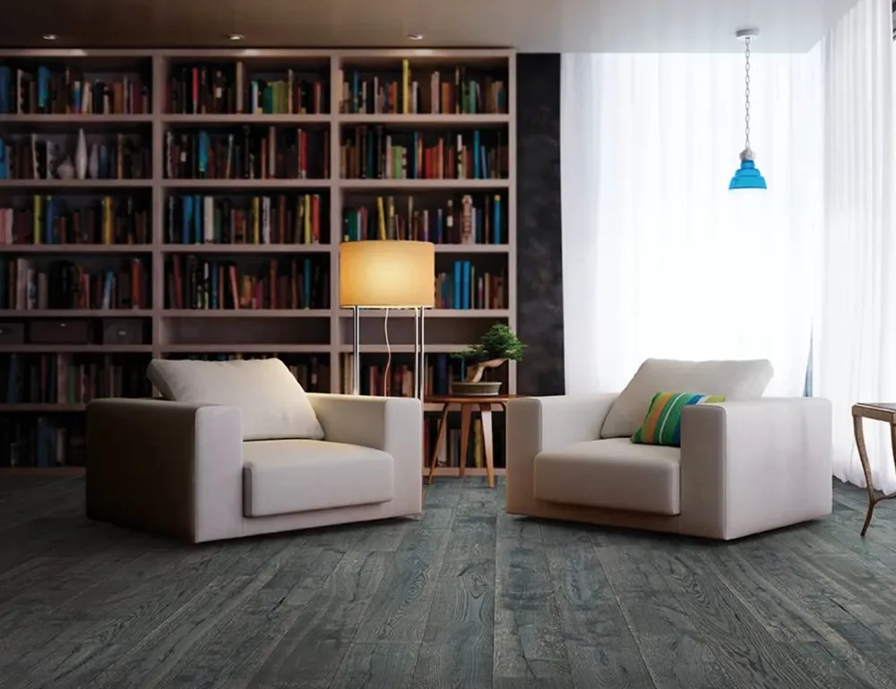 A modern room featuring two beige armchairs on a dark wood floor, with a backdrop of a large bookshelf and a soft floor lamp.