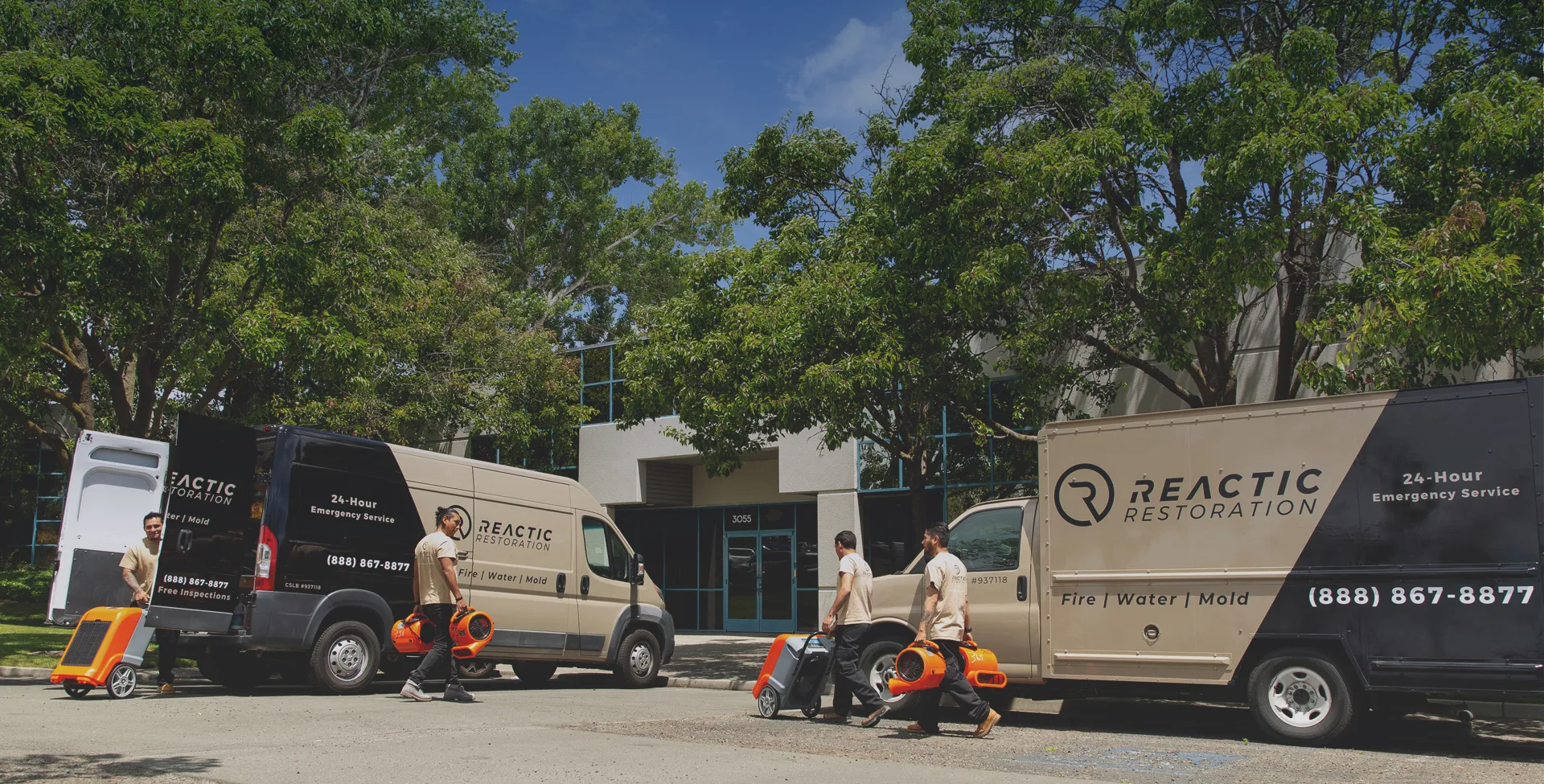Three Reactic Restoration vans parked outside a building in San Pablo, with several team members unloading equipment.