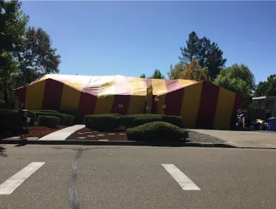 A house in Windsor covered with a large red and yellow tent as part of pest control treatment by Redwood Empire Termite and Pest Control.