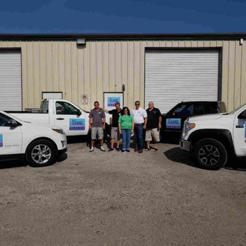 Group of people standing between trucks with logos in front of a warehouse building, representing Restoration Roofing & Remodeling, LLC in Spring.