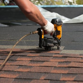 "A hand holding a nail gun installing shingles on a roof, representing Restoration Roofing & Remodeling, LLC's work in Spring."