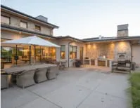 Outdoor patio area of a modern home with seating, a large umbrella, and exterior lighting.