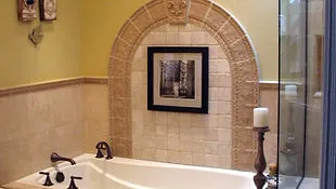 A luxurious bathroom featuring a bathtub with an ornate tile arch and framed artwork, designed by Richard Gallardo Inc. in Gilroy.