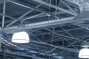 Ceiling with industrial light fixtures and exposed ductwork installed by Roberts Electric Company, Inc. in Oakland.